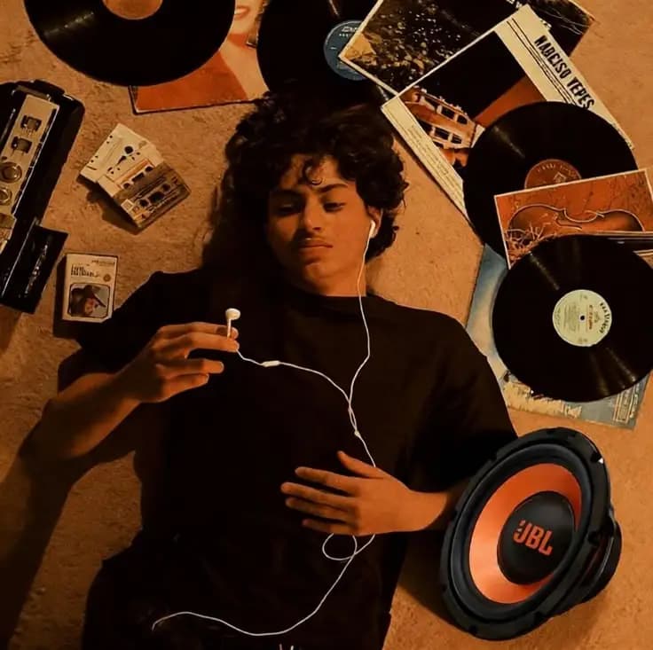Person with earphones lying among vinyl records and cassettes